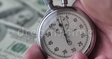 特写一个人在金钱背景上启动秒表。 时间就是金钱。 最后期限概念。